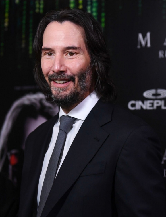 At the premiere of The Matrix Resurrections Keanu Reeves has a long hair and beard with a bright smile-1
