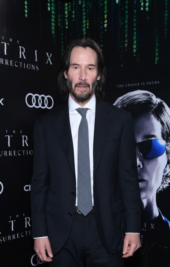 At the premiere of The Matrix Resurrections Keanu Reeves has a long hair and beard with a bright smile-2