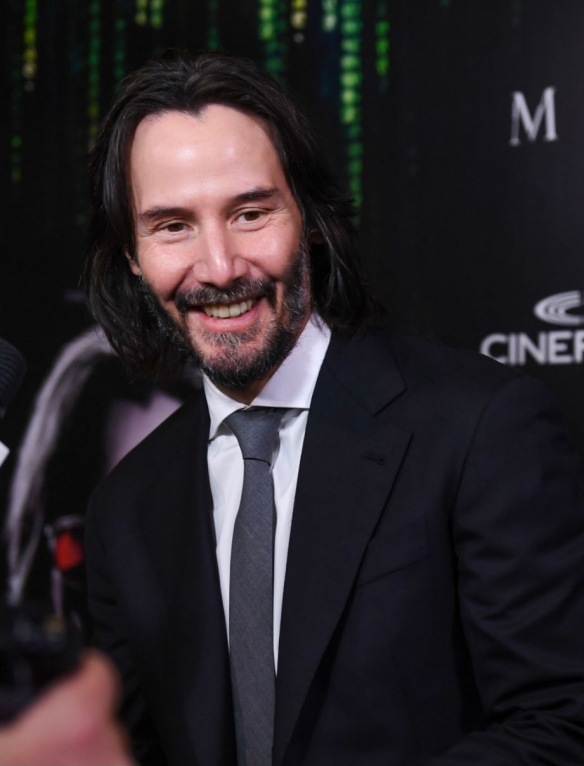 At the premiere of The Matrix Resurrections Keanu Reeves has a long hair and beard with a bright smile-3