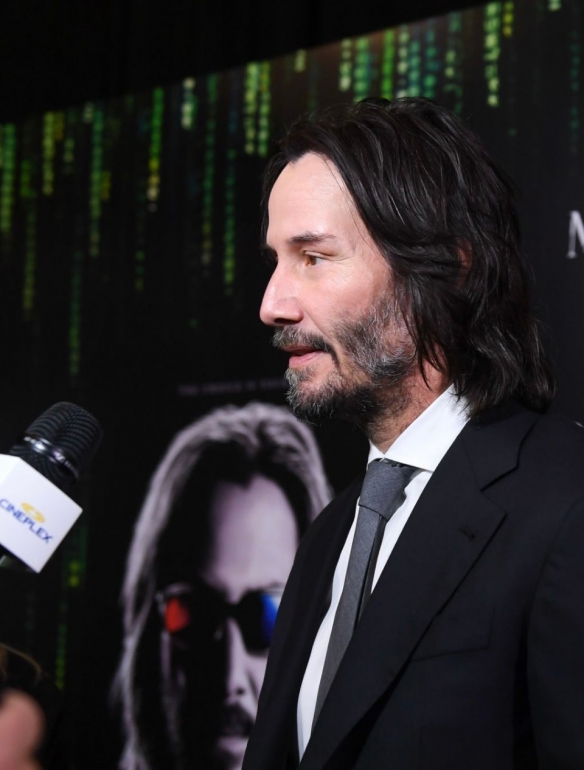 At the premiere of The Matrix Resurrections Keanu Reeves has a long hair and beard with a bright smile-4